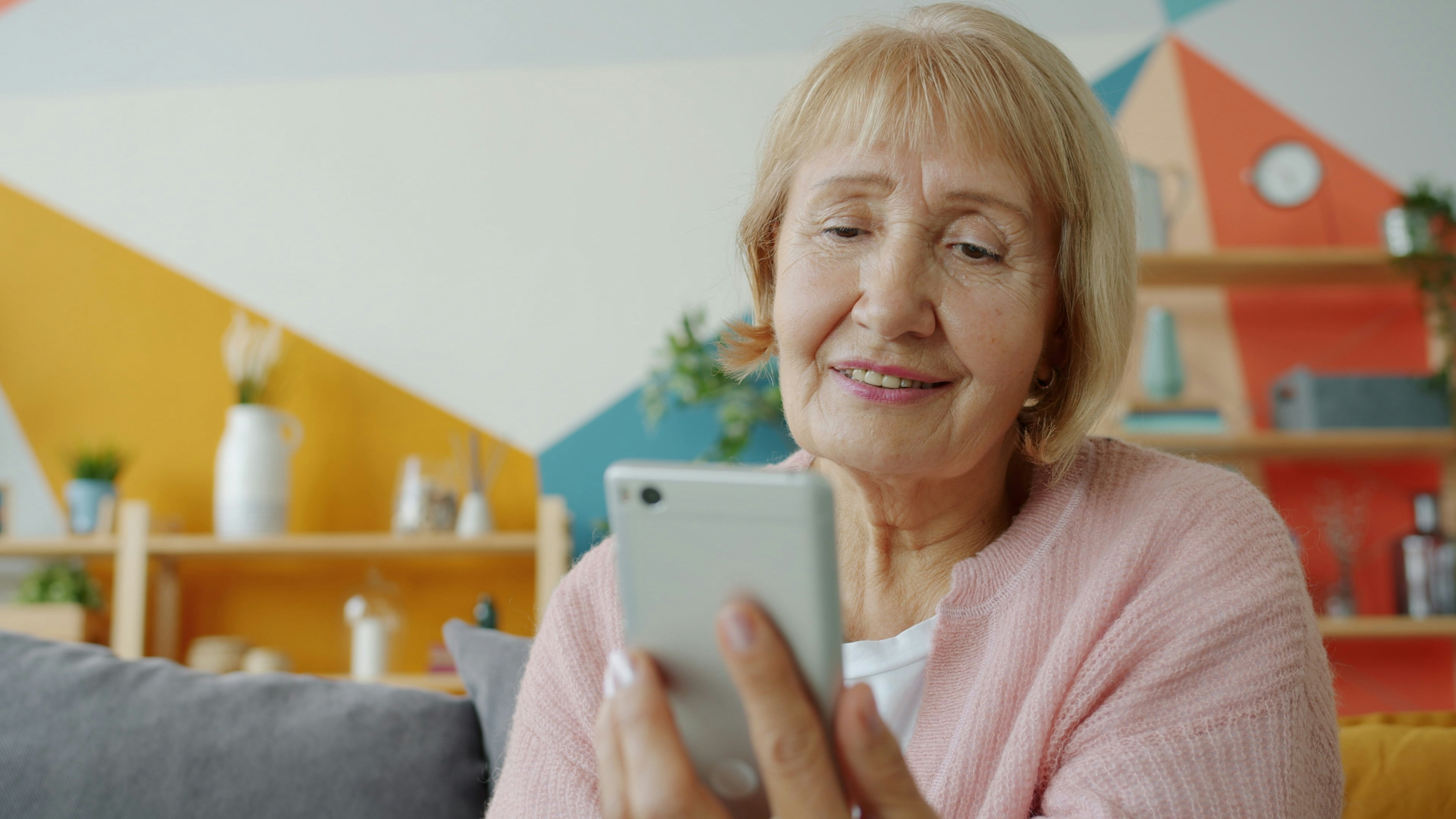 Senior woman smiling at her mobile phone at home